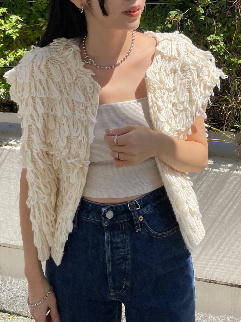 ブルー系のデニムパンツ、ホワイト系のベスト、ブラック系のブーツを着用したレディースの秋コーディネートの5枚目の写真