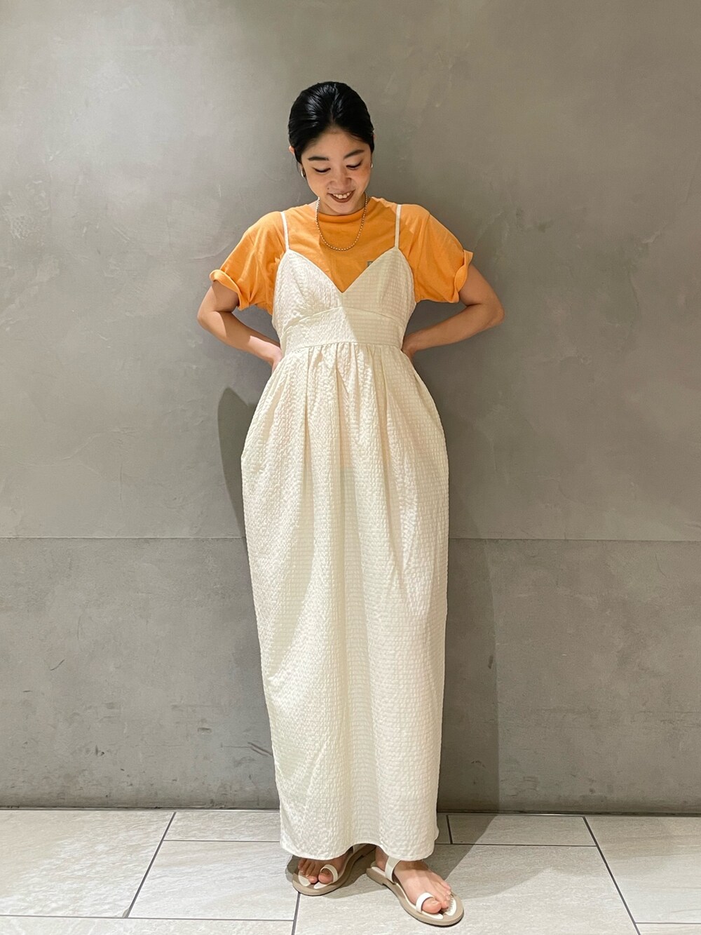 ホワイト系のワンピース、オレンジ系のTシャツ/カットソー、ホワイト系のサンダルを着用したレディースの夏コーディネートの4枚目の写真