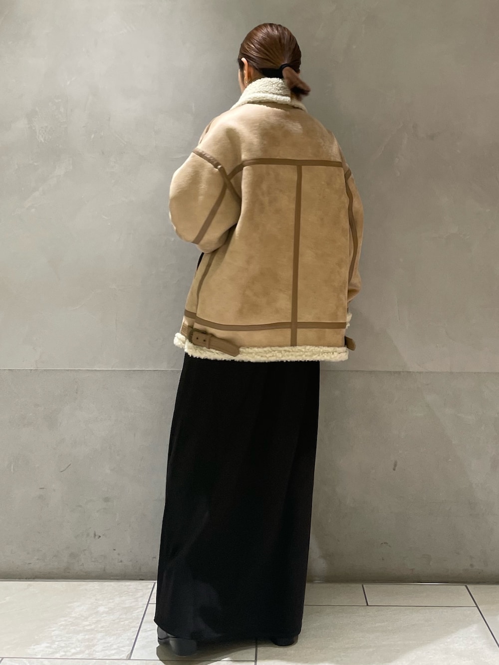 ベージュ系のムートンコート、ブラック系のTシャツ/カットソー、ブラック系のスカートを着用したレディースの秋コーディネートの4枚目の写真