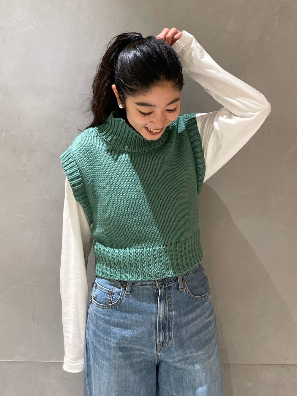 ブルー系のデニムパンツ、グリーン系のワンピース、ゴールド系のパンプスを着用したレディースの冬コーディネートの7枚目の写真