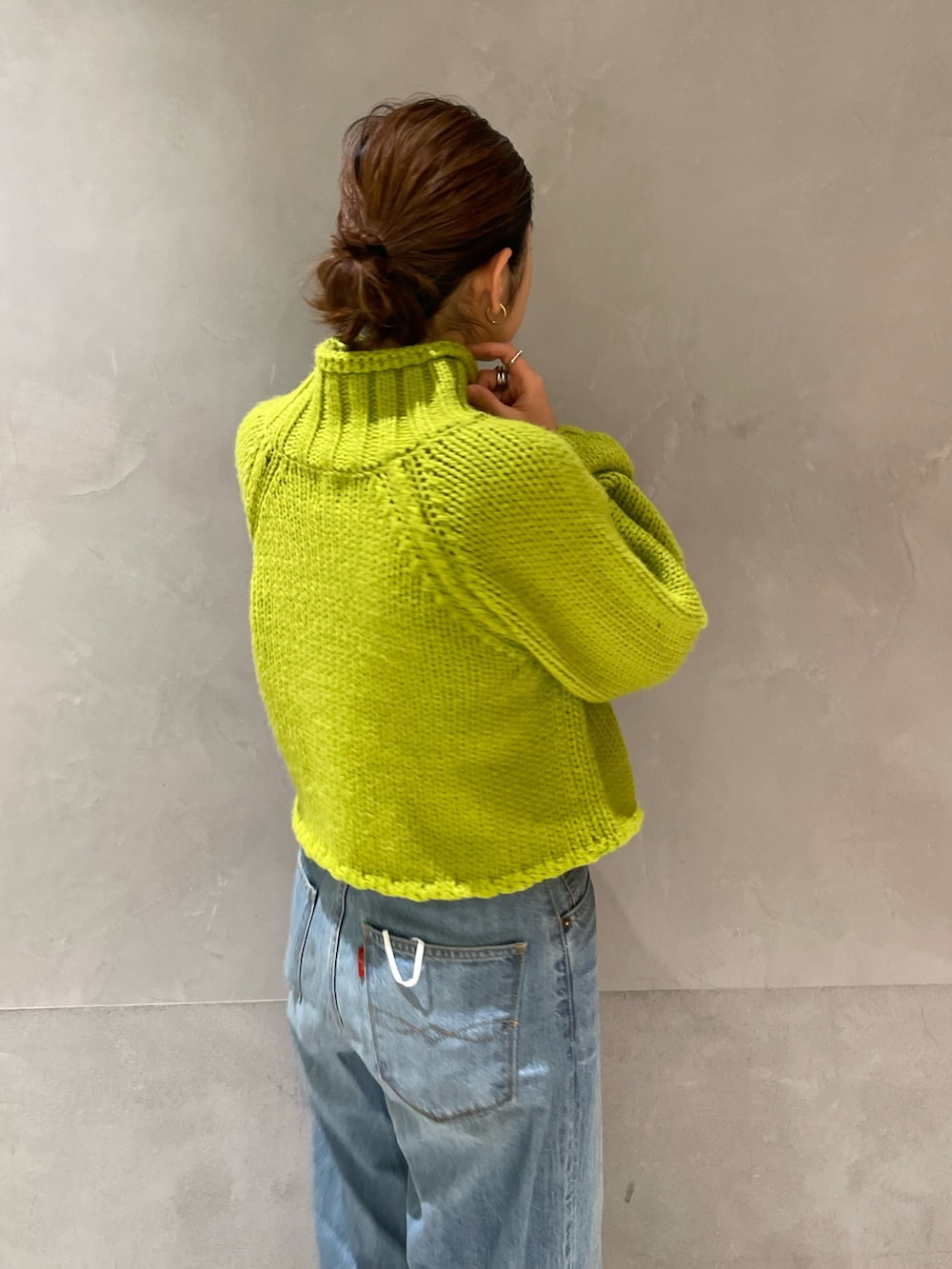 グリーン系のニット/セーター、ブルー系のデニムパンツ、ホワイト系のブーツを着用したレディースの冬コーディネートの2枚目の写真