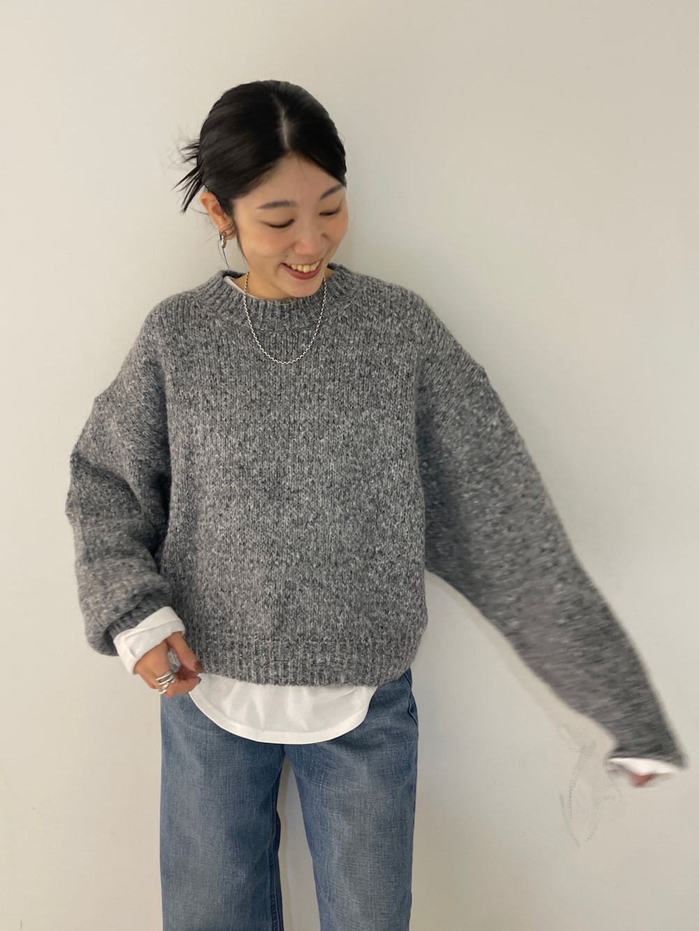 グレー系のニット/セーター、ブルー系のデニムパンツ、ブラック系のブルゾンを着用したレディースの秋コーディネートの5枚目の写真
