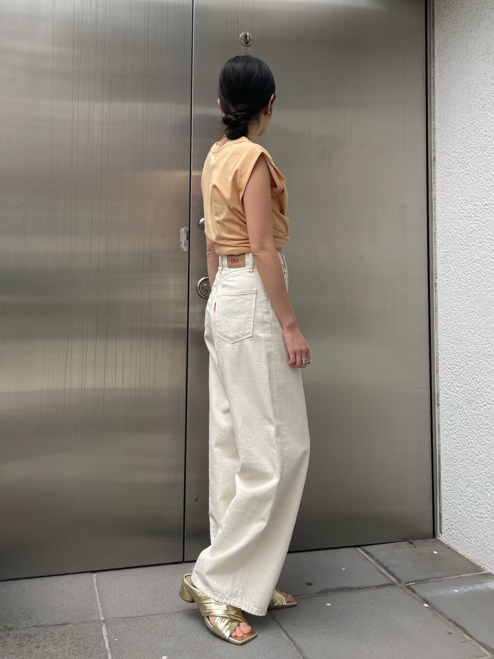 ホワイト系のデニムパンツ、ゴールド系のサンダルを着用したレディースの春コーディネートの3枚目の写真