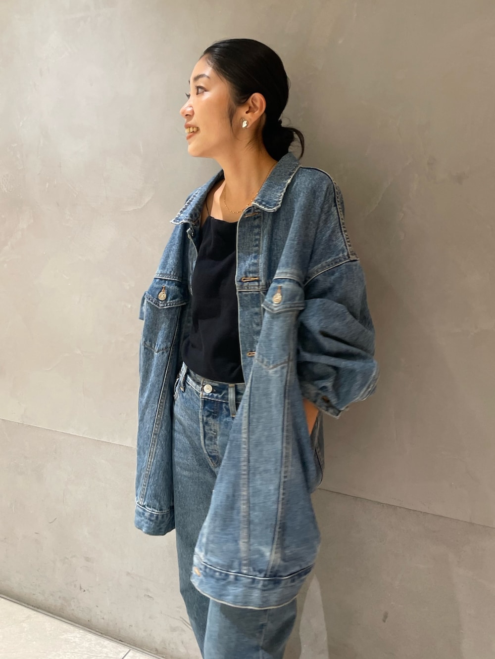 ブルー系のデニムジャケット、ブルー系のデニムパンツ、ブラック系のキャミソールを着用したレディースの秋コーディネートの2枚目の写真