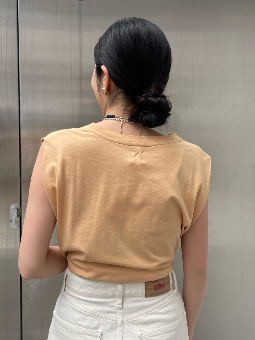 ホワイト系のデニムパンツ、ゴールド系のサンダルを着用したレディースの春コーディネートの4枚目の写真