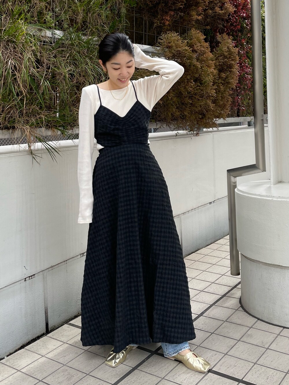 ブラック系のワンピース、ゴールド系のパンプス、ブルー系のデニムパンツを着用したレディースの冬コーディネートの5枚目の写真