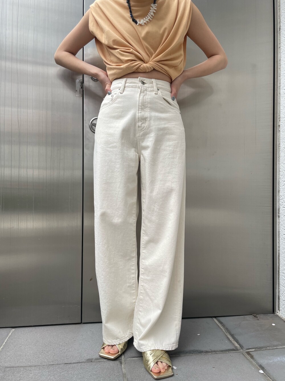 ホワイト系のデニムパンツ、ゴールド系のサンダルを着用したレディースの春コーディネートの5枚目の写真