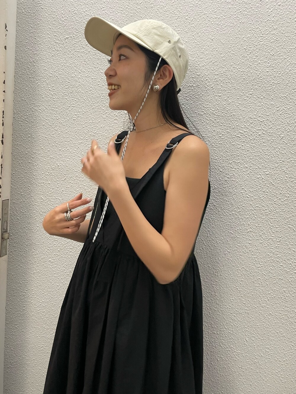 ブラック系のワンピース、ホワイト系のキャップを着用したレディースの春コーディネートの2枚目の写真