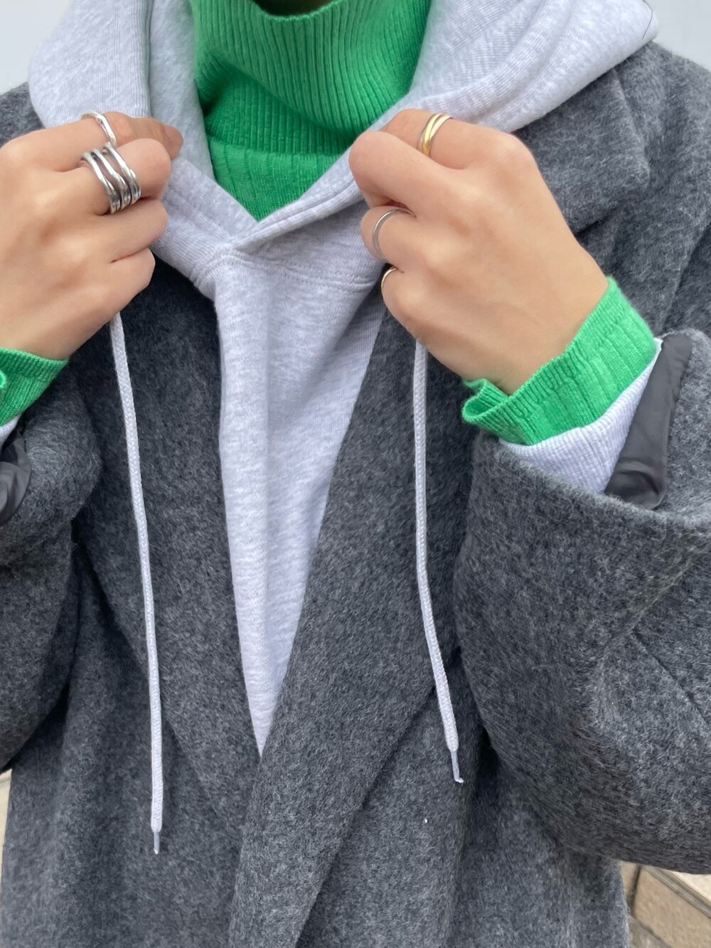 グレー系のパーカー、グリーン系のニット/セーター、ブルー系のデニムパンツを着用したレディースの秋コーディネートの7枚目の写真