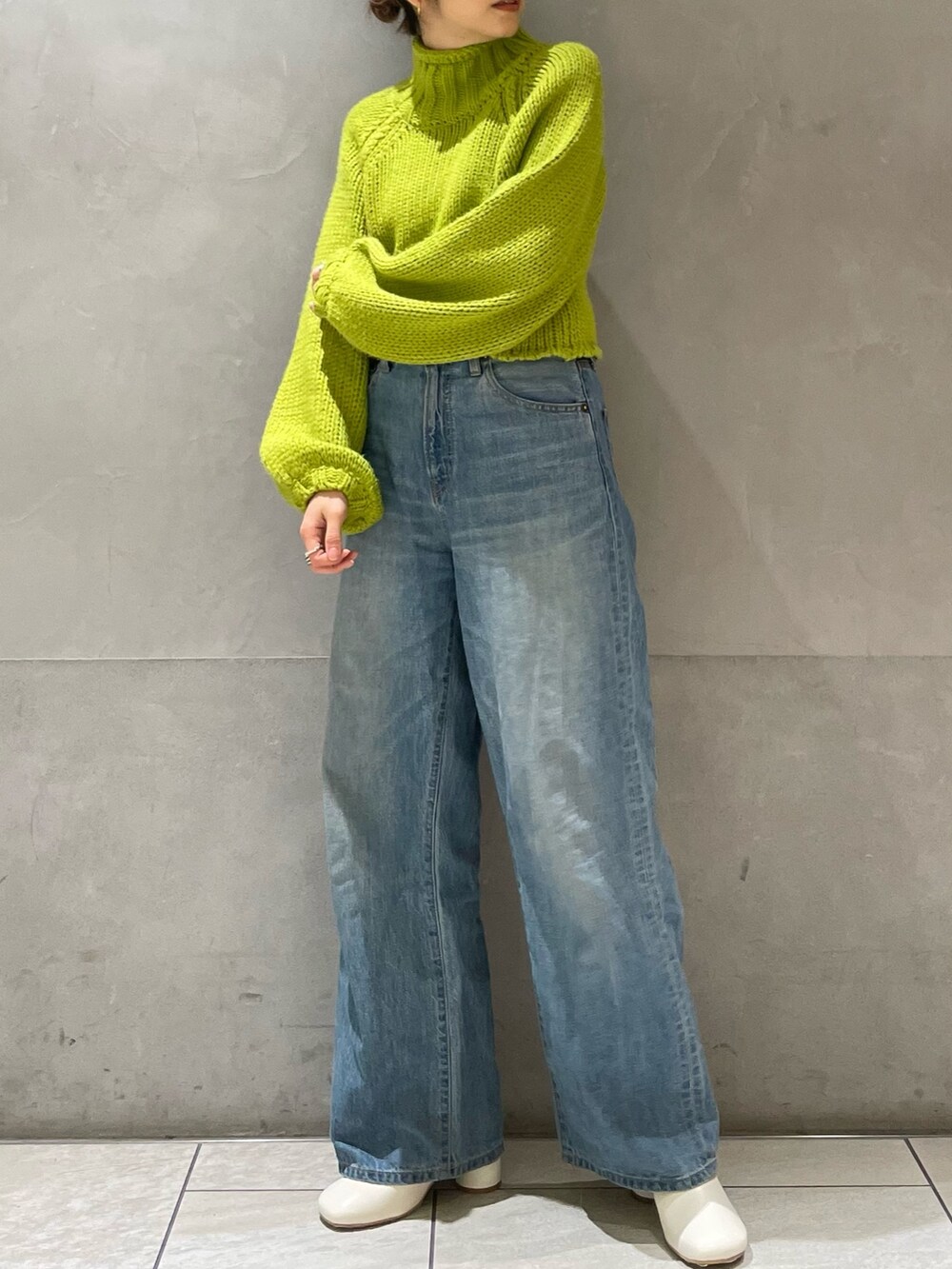 グリーン系のニット/セーター、ブルー系のデニムパンツ、ホワイト系のブーツを着用したレディースの冬コーディネートの4枚目の写真