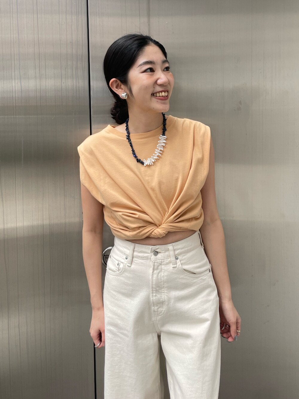 ホワイト系のデニムパンツ、ゴールド系のサンダルを着用したレディースの春コーディネートの2枚目の写真