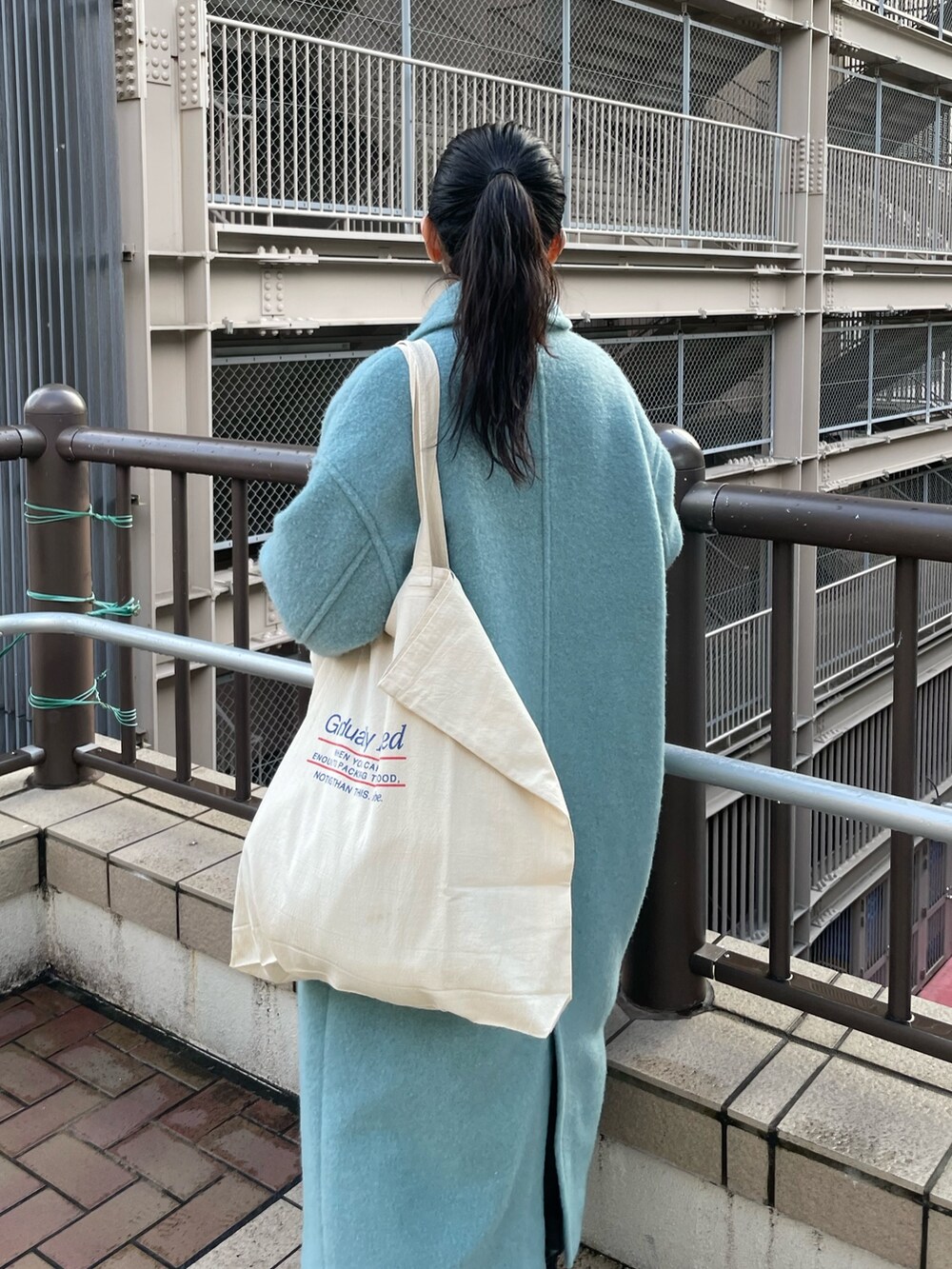 ブルー系のチェスターコート、ホワイト系のニット/セーターを着用したレディースの冬コーディネートの4枚目の写真