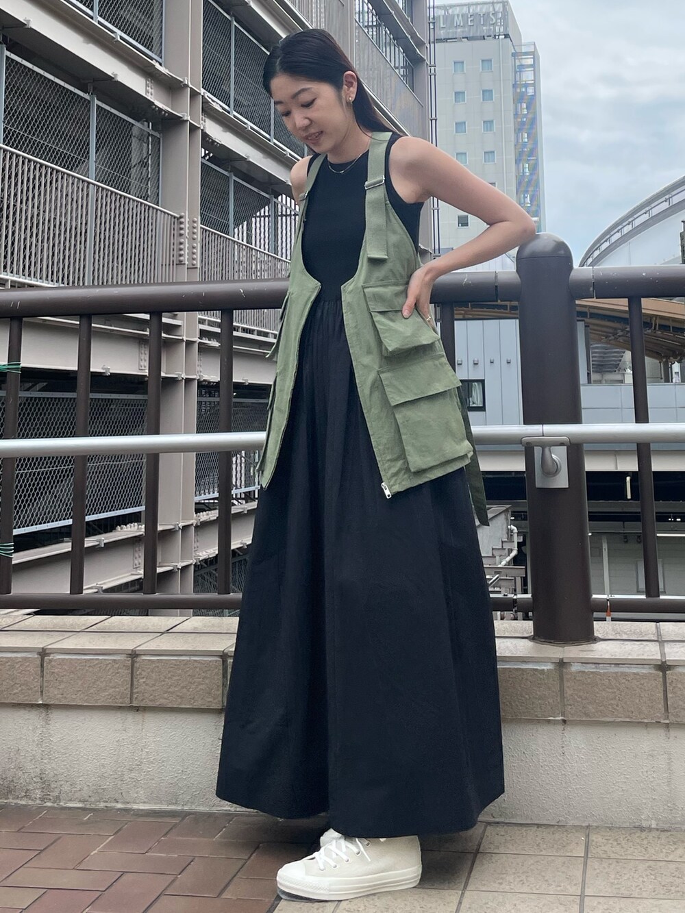 ブラック系のワンピース、ベージュ系のベスト、ホワイト系のスニーカーを着用したレディースの春コーディネートの2枚目の写真