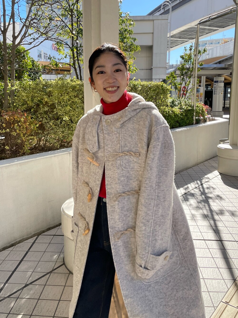 ホワイト系のダッフルコート、レッド系のニット/セーター、ブルー系のデニムパンツを着用したレディースの冬コーディネートの2枚目の写真