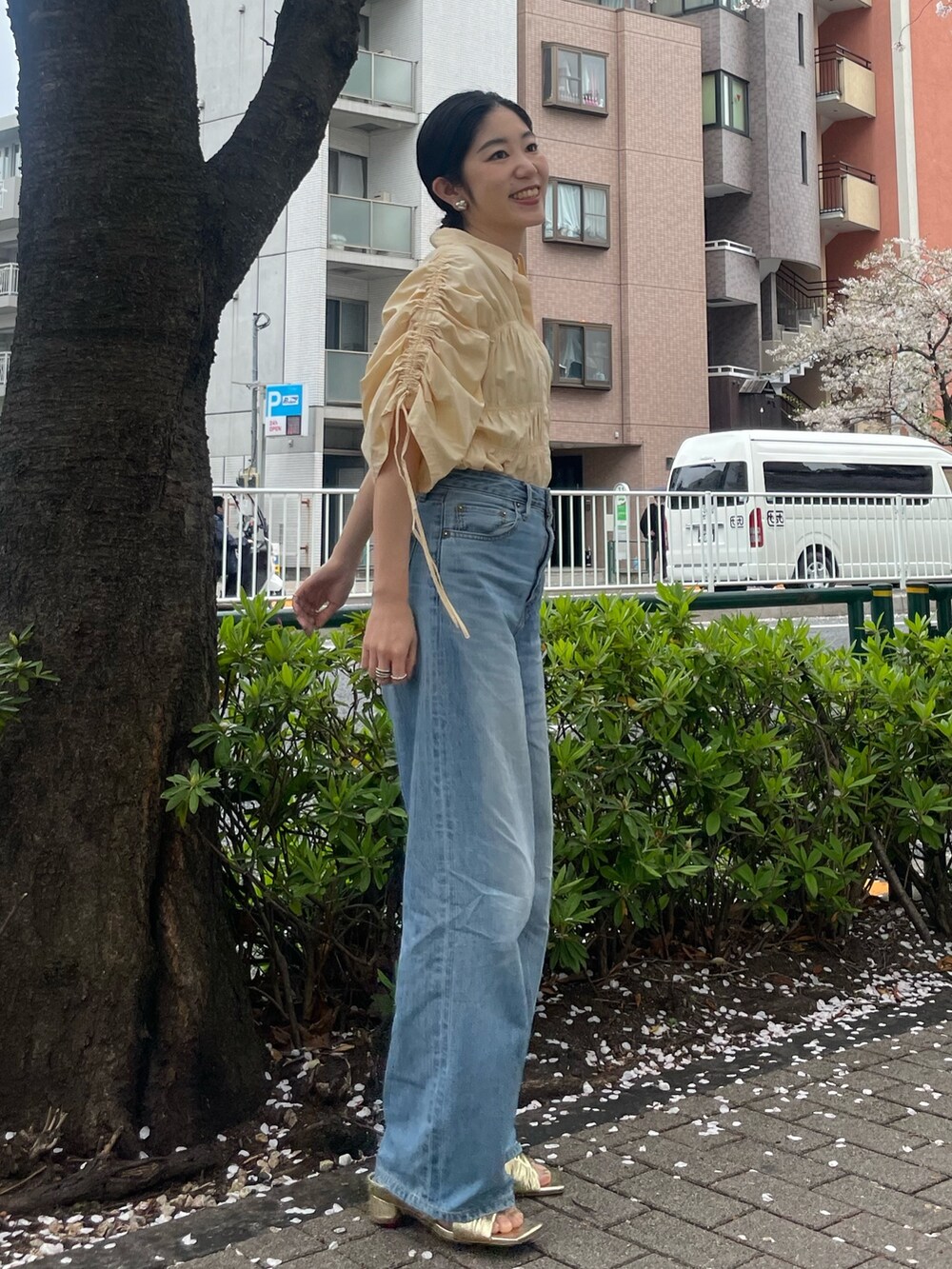 イエロー系のシャツ/ブラウス、ゴールド系のサンダル、ブルー系のデニムパンツを着用したレディースの春コーディネートの2枚目の写真