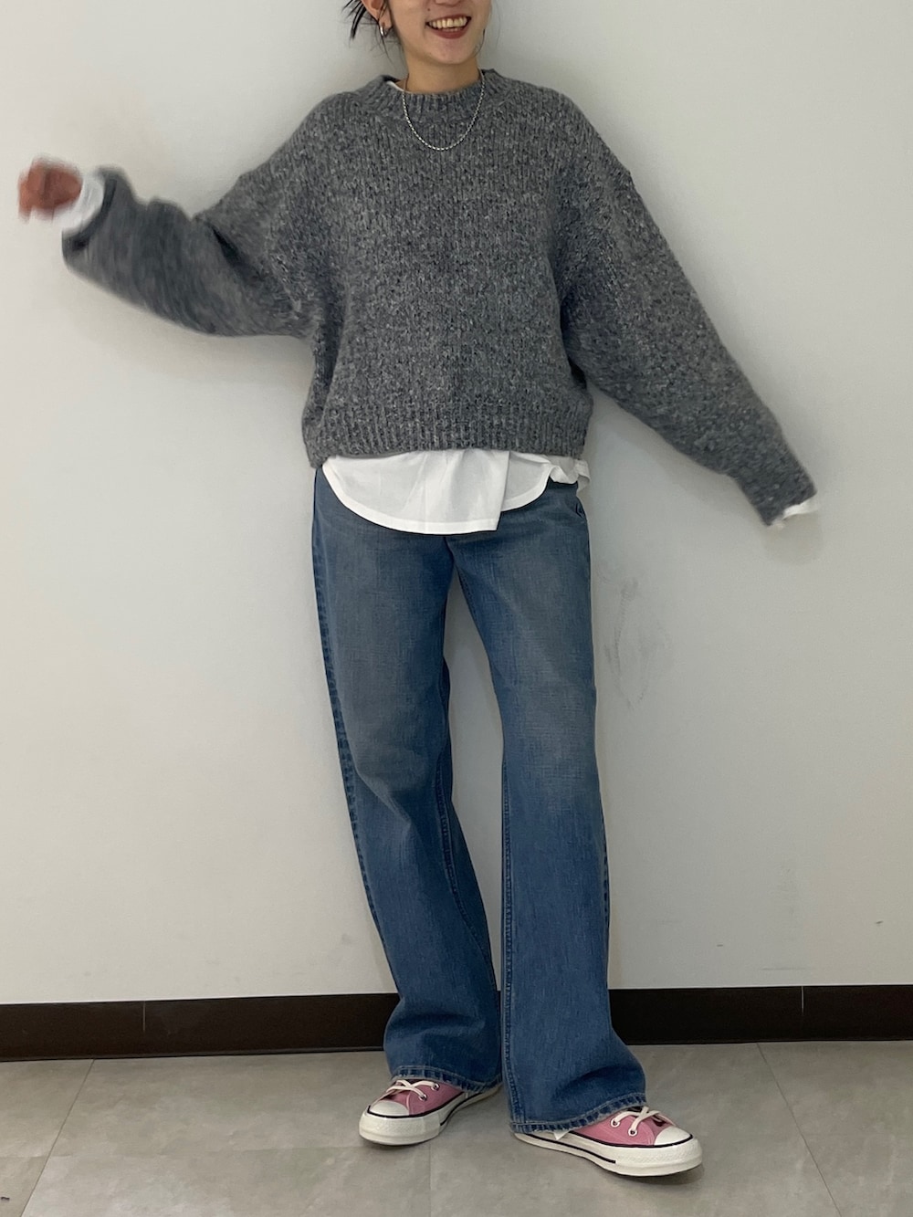 グレー系のニット/セーター、ブルー系のデニムパンツ、ブラック系のブルゾンを着用したレディースの秋コーディネートの6枚目の写真