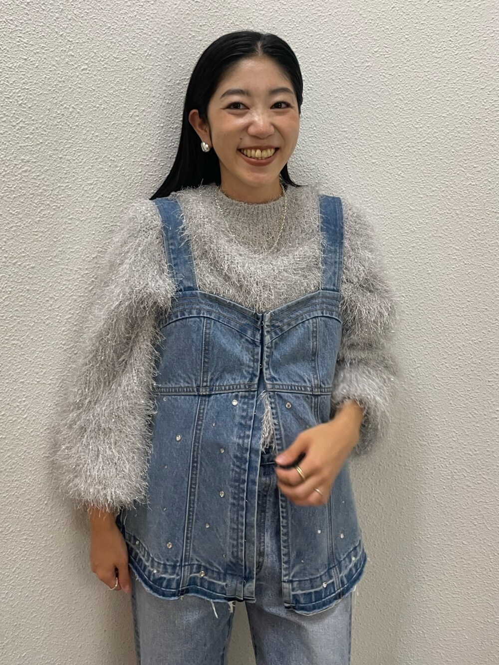 シルバー系のニット/セーター、ブルー系のタンクトップ、ブルー系のデニムパンツを着用したレディースの秋コーディネートの3枚目の写真