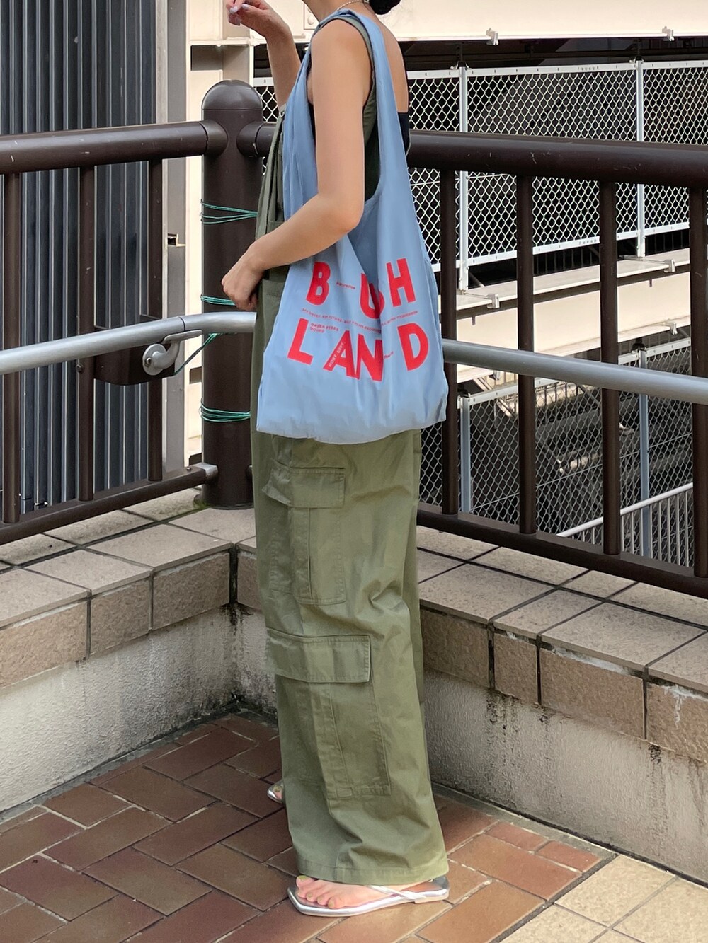 グリーン系のサロペット/オーバーオール、ブルー系のエコバッグ/サブバッグ、ブラック系のキャミソールを着用したレディースの夏コーディネートの2枚目の写真