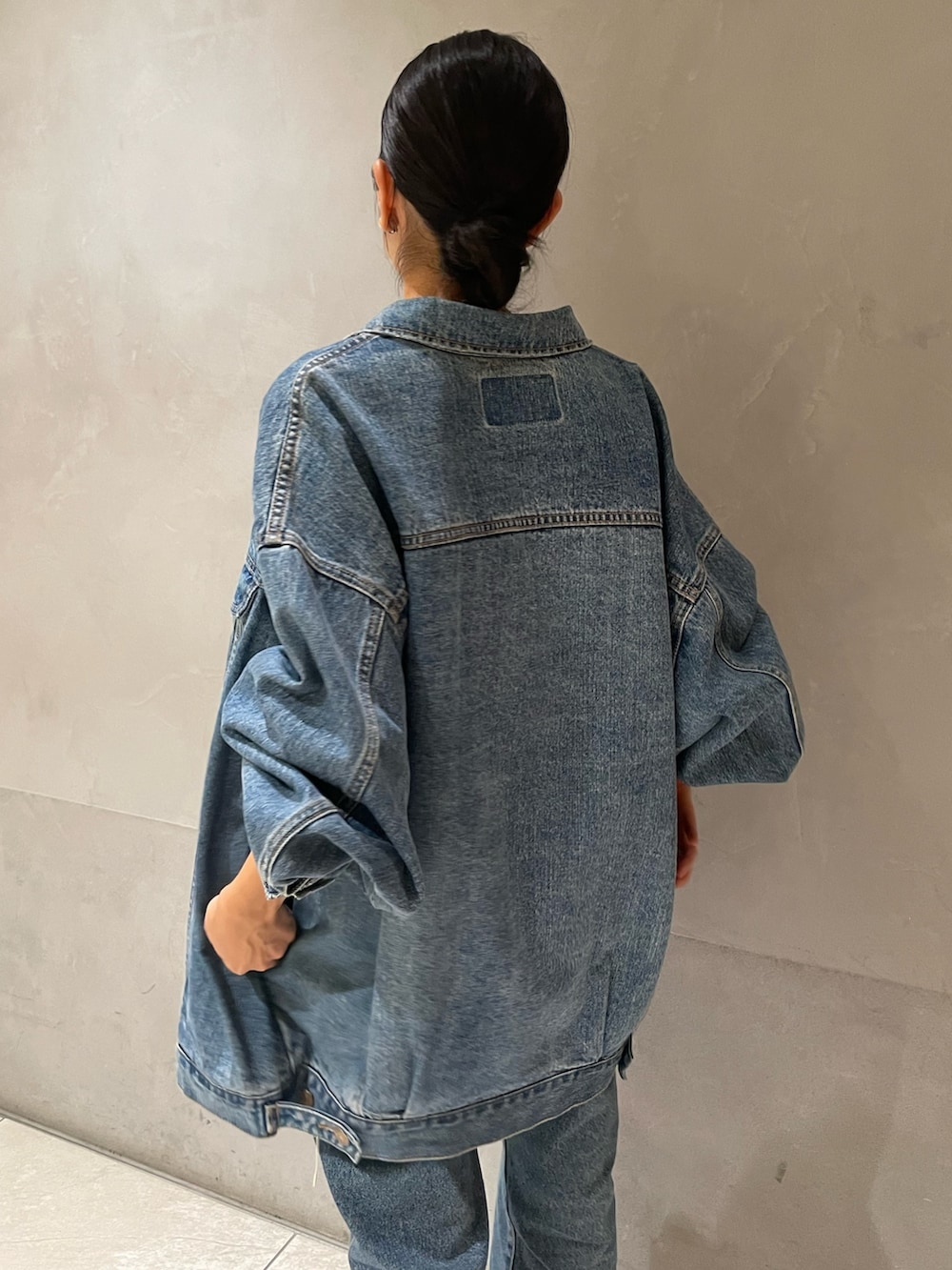 ブルー系のデニムジャケット、ブルー系のデニムパンツ、ブラック系のキャミソールを着用したレディースの秋コーディネートの3枚目の写真