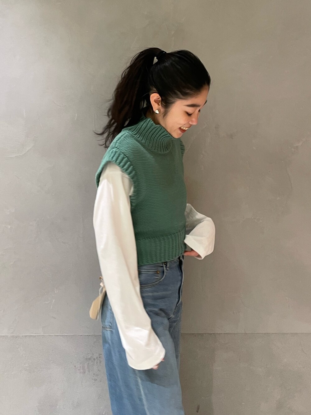 ブルー系のデニムパンツ、グリーン系のワンピース、ゴールド系のパンプスを着用したレディースの冬コーディネートの5枚目の写真