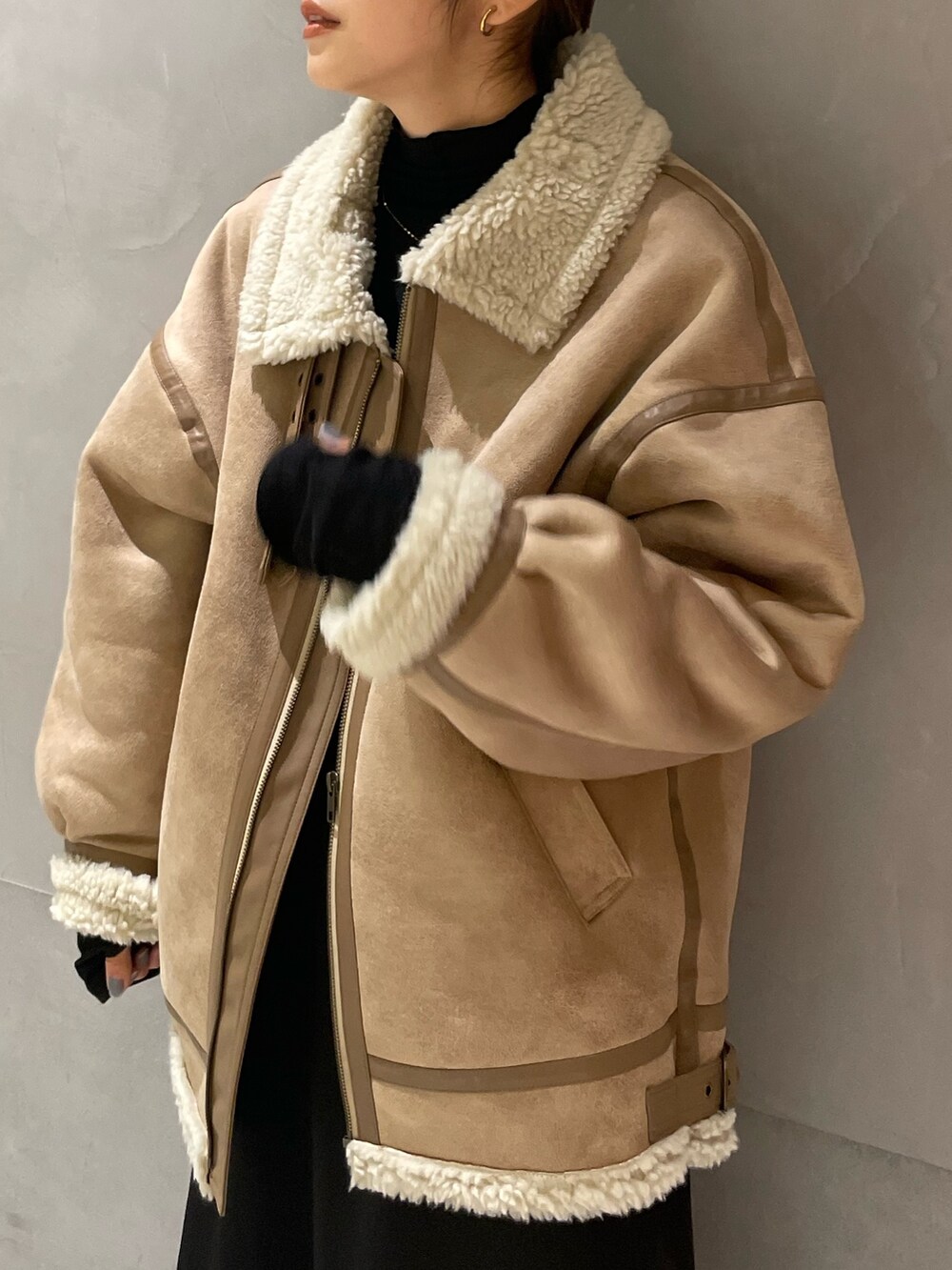 ベージュ系のムートンコート、ブラック系のTシャツ/カットソー、ブラック系のスカートを着用したレディースの秋コーディネートの5枚目の写真