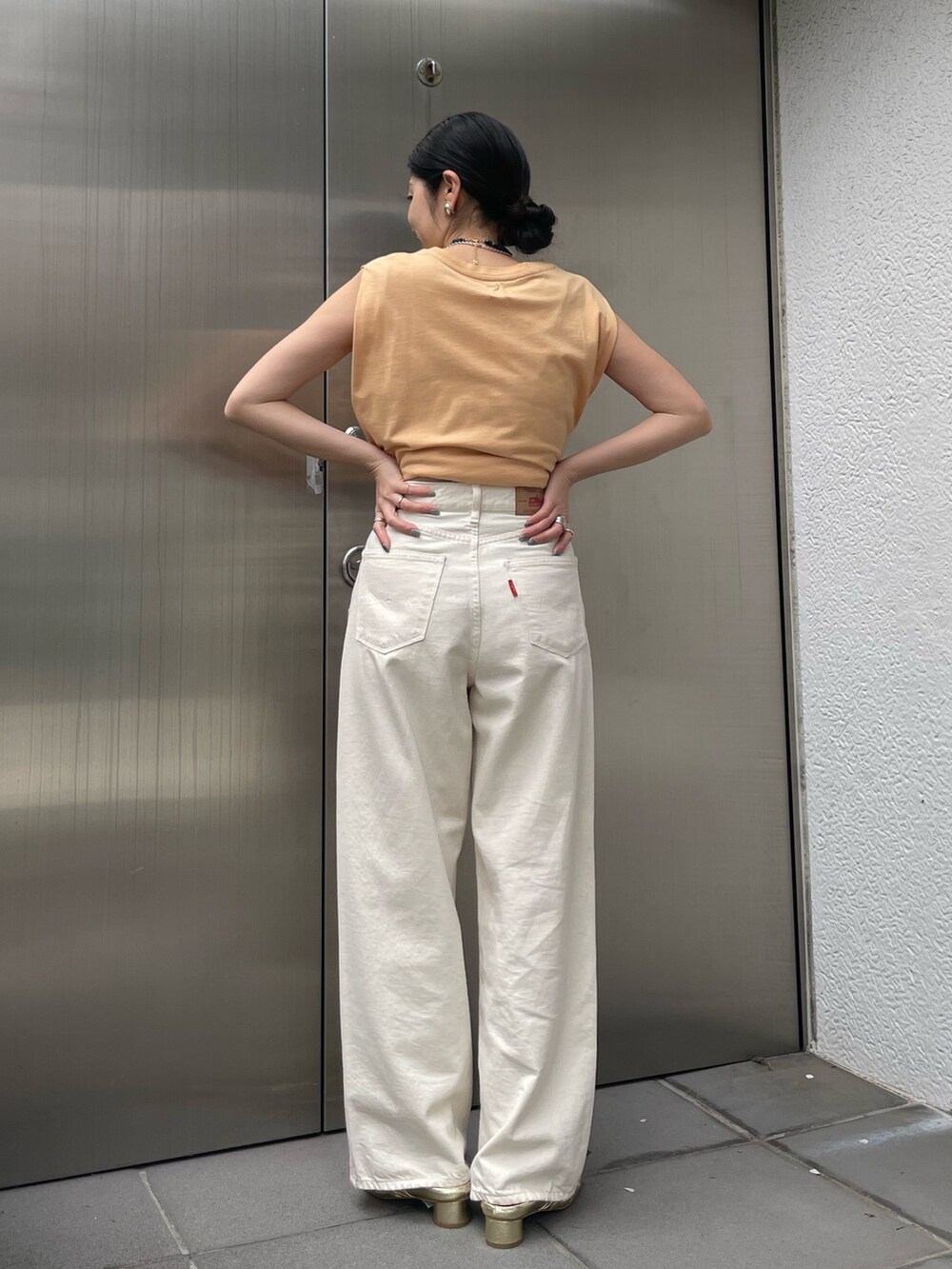 ホワイト系のデニムパンツ、ゴールド系のサンダルを着用したレディースの春コーディネートの6枚目の写真