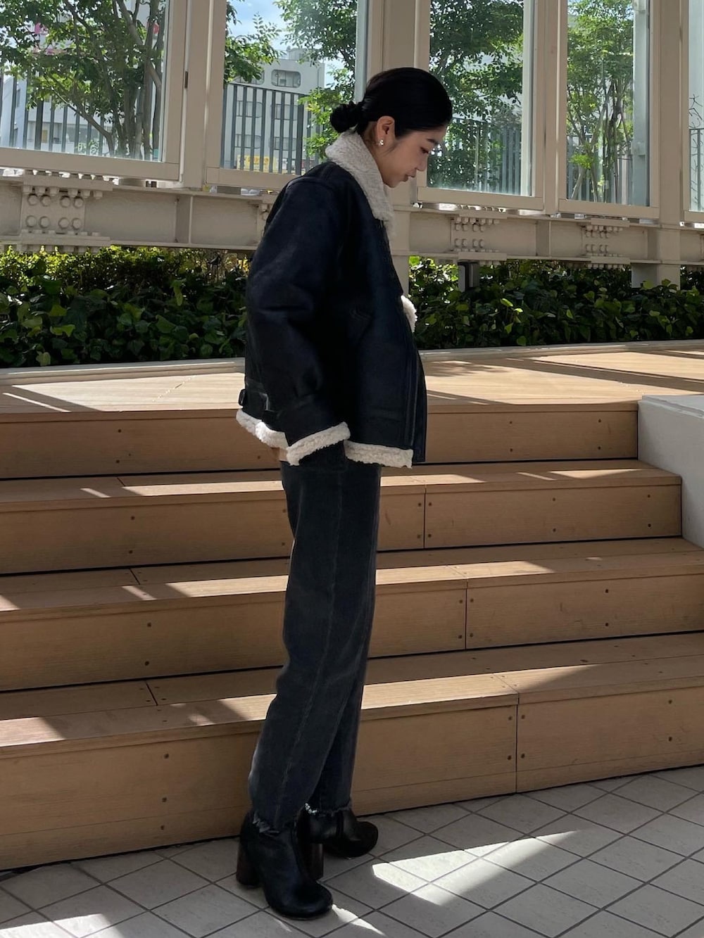 ブラック系のムートンコート、グレー系のニット/セーター、ブラック系のデニムパンツを着用したレディースの秋コーディネートの5枚目の写真