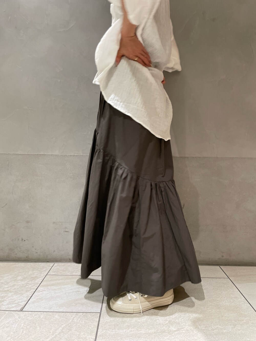 グレー系のスカート、ホワイト系のスニーカー、ホワイト系のシャツ/ブラウスを着用したレディースの春コーディネートの5枚目の写真