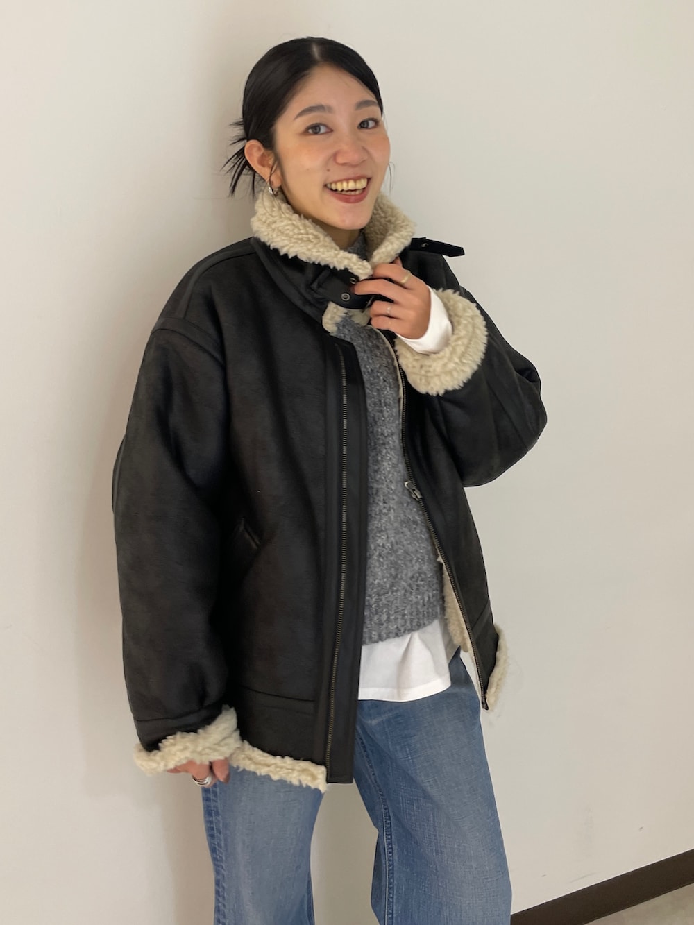 グレー系のニット/セーター、ブルー系のデニムパンツ、ブラック系のブルゾンを着用したレディースの秋コーディネートの3枚目の写真