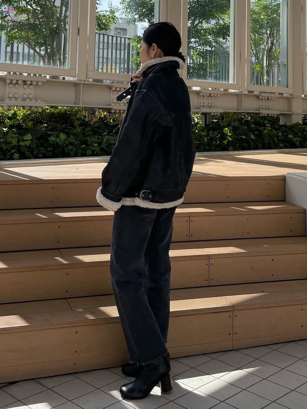 ブラック系のムートンコート、グレー系のニット/セーター、ブラック系のデニムパンツを着用したレディースの秋コーディネートの4枚目の写真