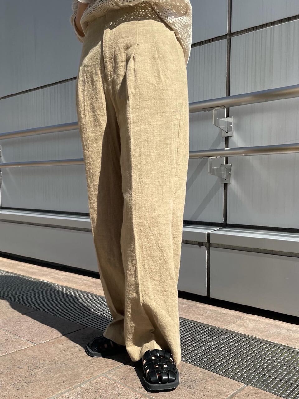 ベージュ系のその他パンツ、ブラック系のサンダル、ホワイト系のTシャツ/カットソーを着用したレディースの春コーディネートの6枚目の写真