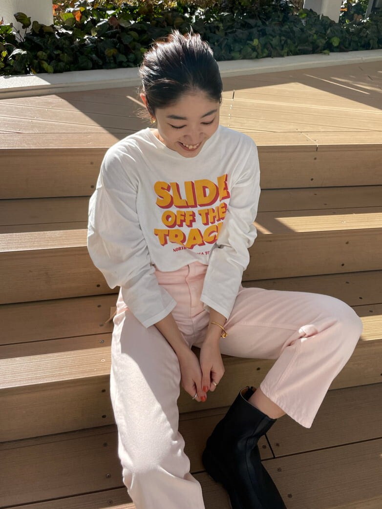 ベージュ系のステンカラーコート、ブラック系のブーツ、ホワイト系のTシャツ/カットソーを着用したレディースの冬コーディネートの4枚目の写真