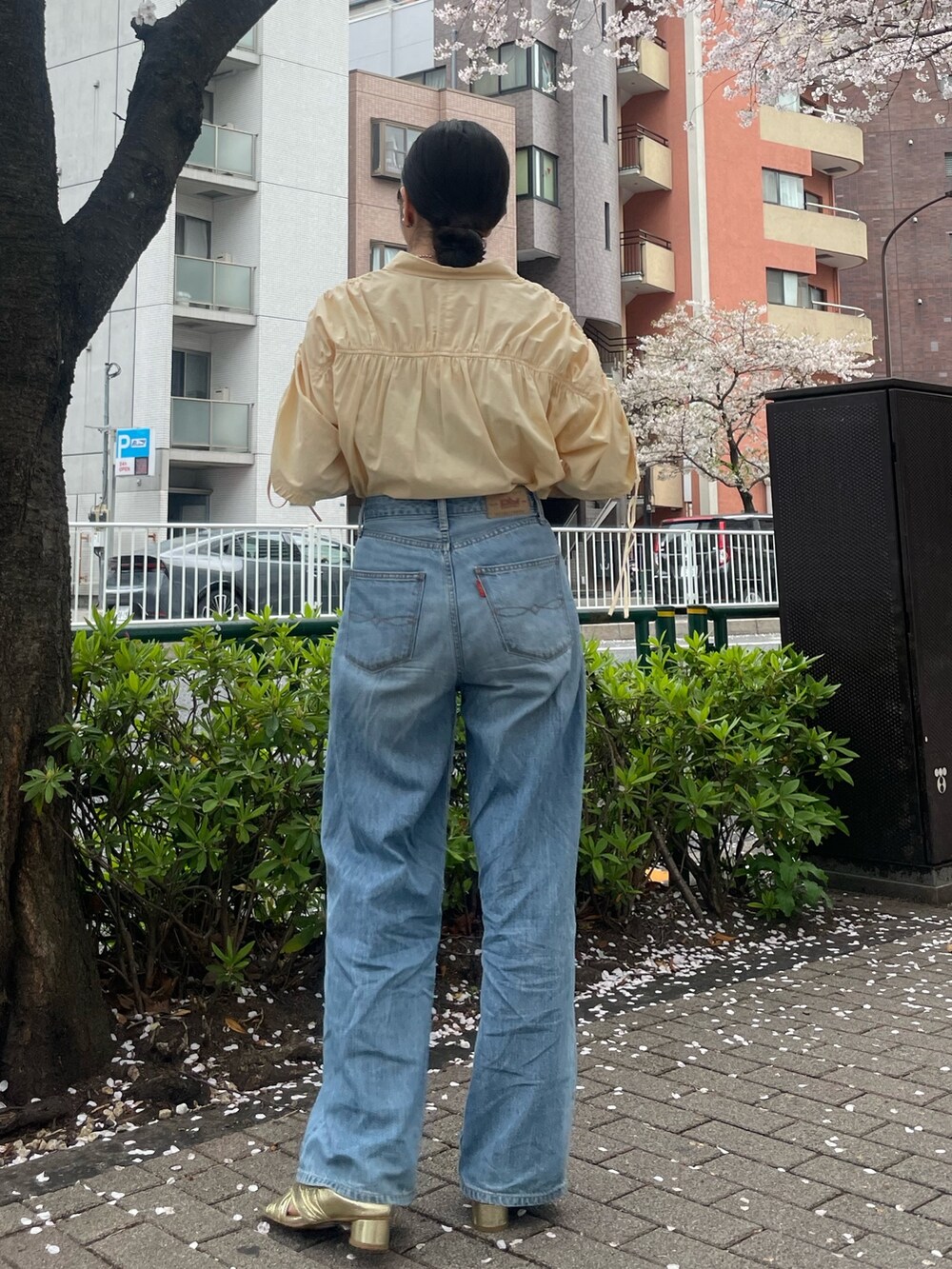 イエロー系のシャツ/ブラウス、ゴールド系のサンダル、ブルー系のデニムパンツを着用したレディースの春コーディネートの4枚目の写真