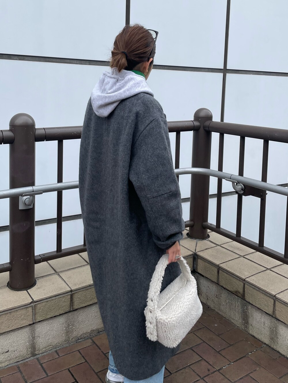 グレー系のパーカー、グリーン系のニット/セーター、ブルー系のデニムパンツを着用したレディースの秋コーディネートの4枚目の写真