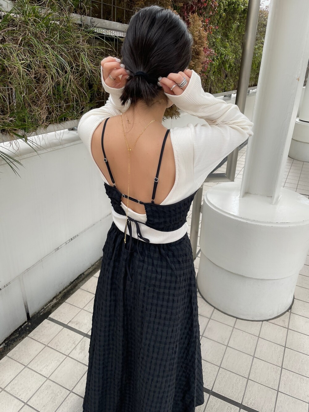 ブラック系のワンピース、ゴールド系のパンプス、ブルー系のデニムパンツを着用したレディースの冬コーディネートの2枚目の写真