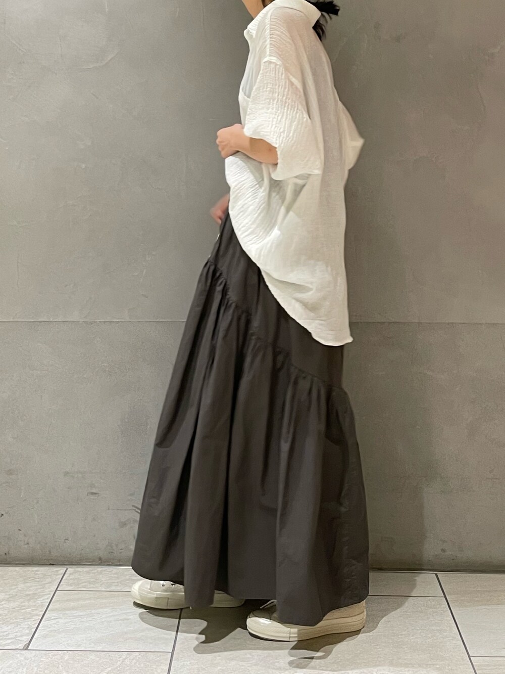グレー系のスカート、ホワイト系のスニーカー、ホワイト系のシャツ/ブラウスを着用したレディースの春コーディネートの3枚目の写真