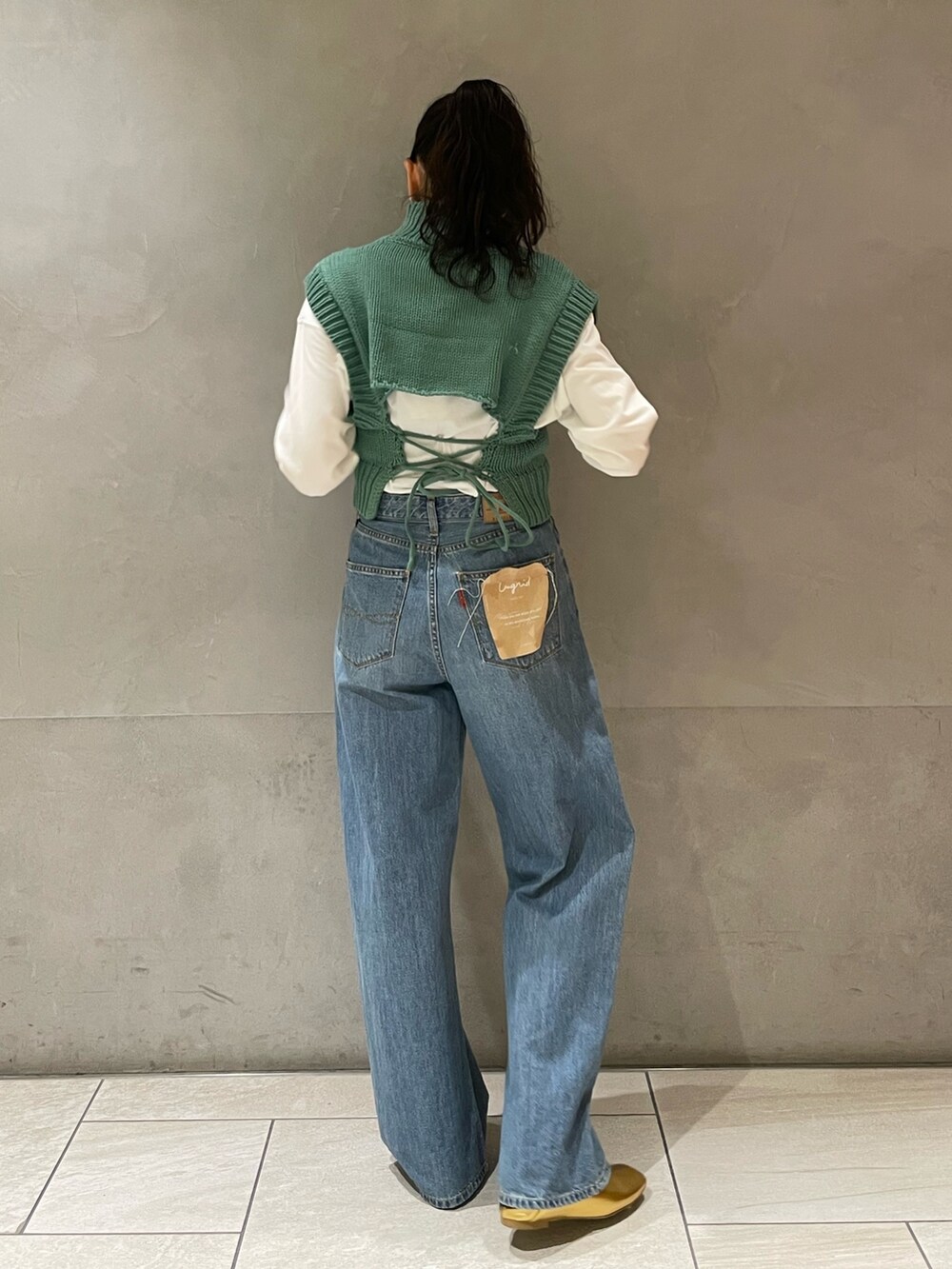 ブルー系のデニムパンツ、グリーン系のワンピース、ゴールド系のパンプスを着用したレディースの冬コーディネートの3枚目の写真