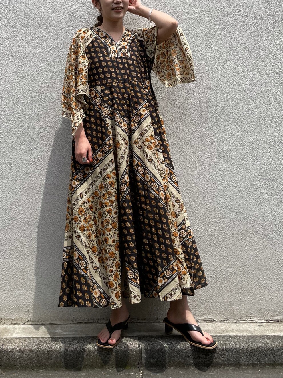 ブラック系のサンダル、イエロー系のワンピースを着用したレディースの夏コーディネートの3枚目の写真