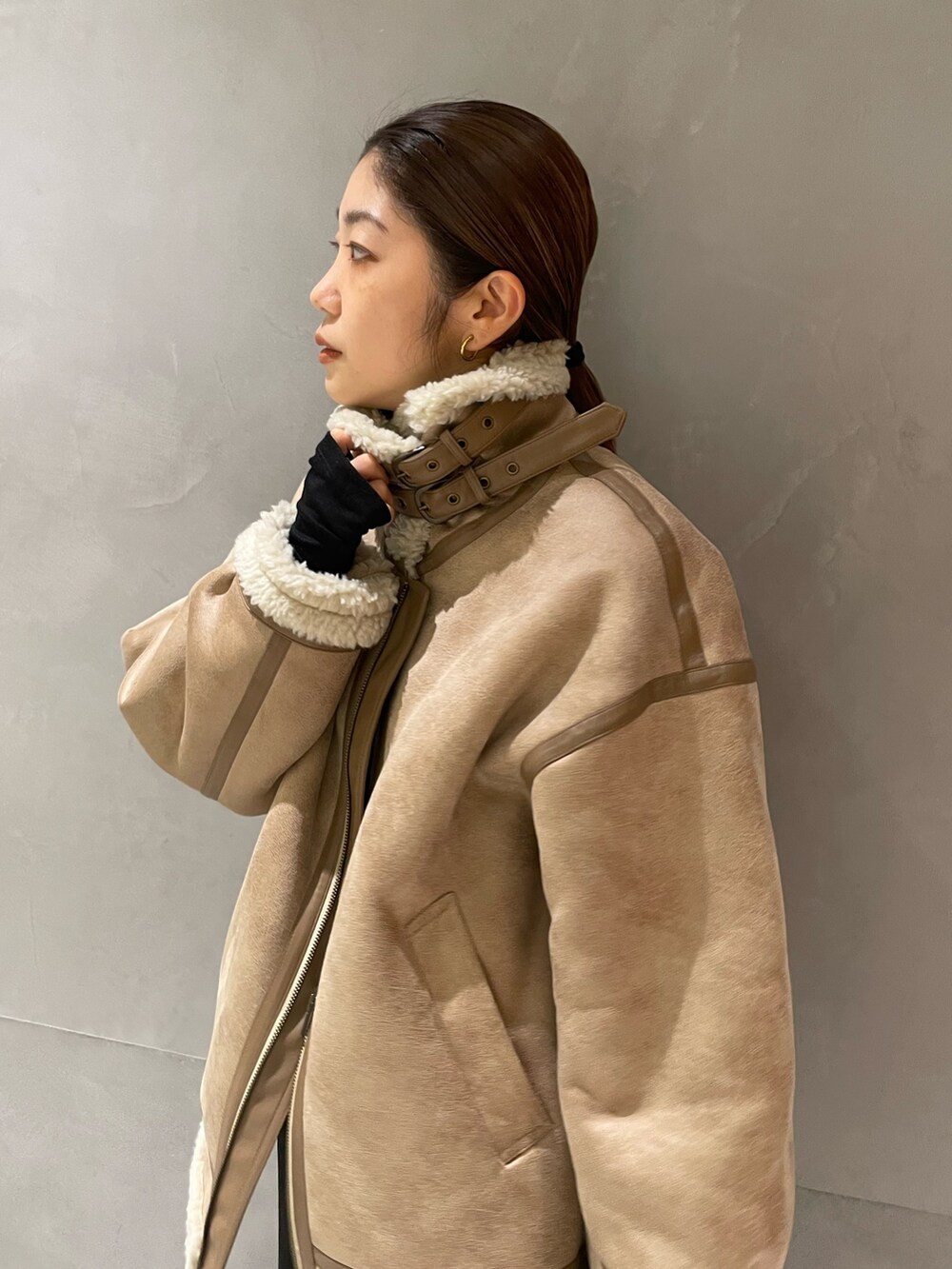 ベージュ系のムートンコート、ブラック系のTシャツ/カットソー、ブラック系のスカートを着用したレディースの秋コーディネートの3枚目の写真