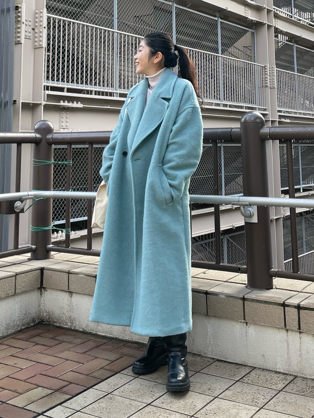 ブルー系のチェスターコート、ホワイト系のニット/セーターを着用したレディースの冬コーディネートの3枚目の写真