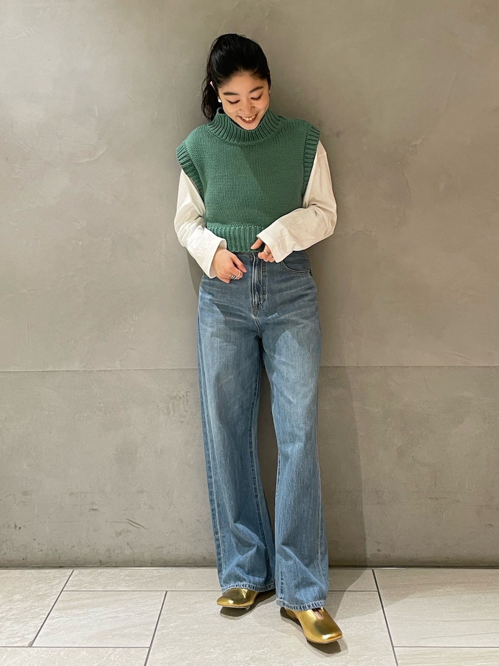 ブルー系のデニムパンツ、グリーン系のワンピース、ゴールド系のパンプスを着用したレディースの冬コーディネートの2枚目の写真