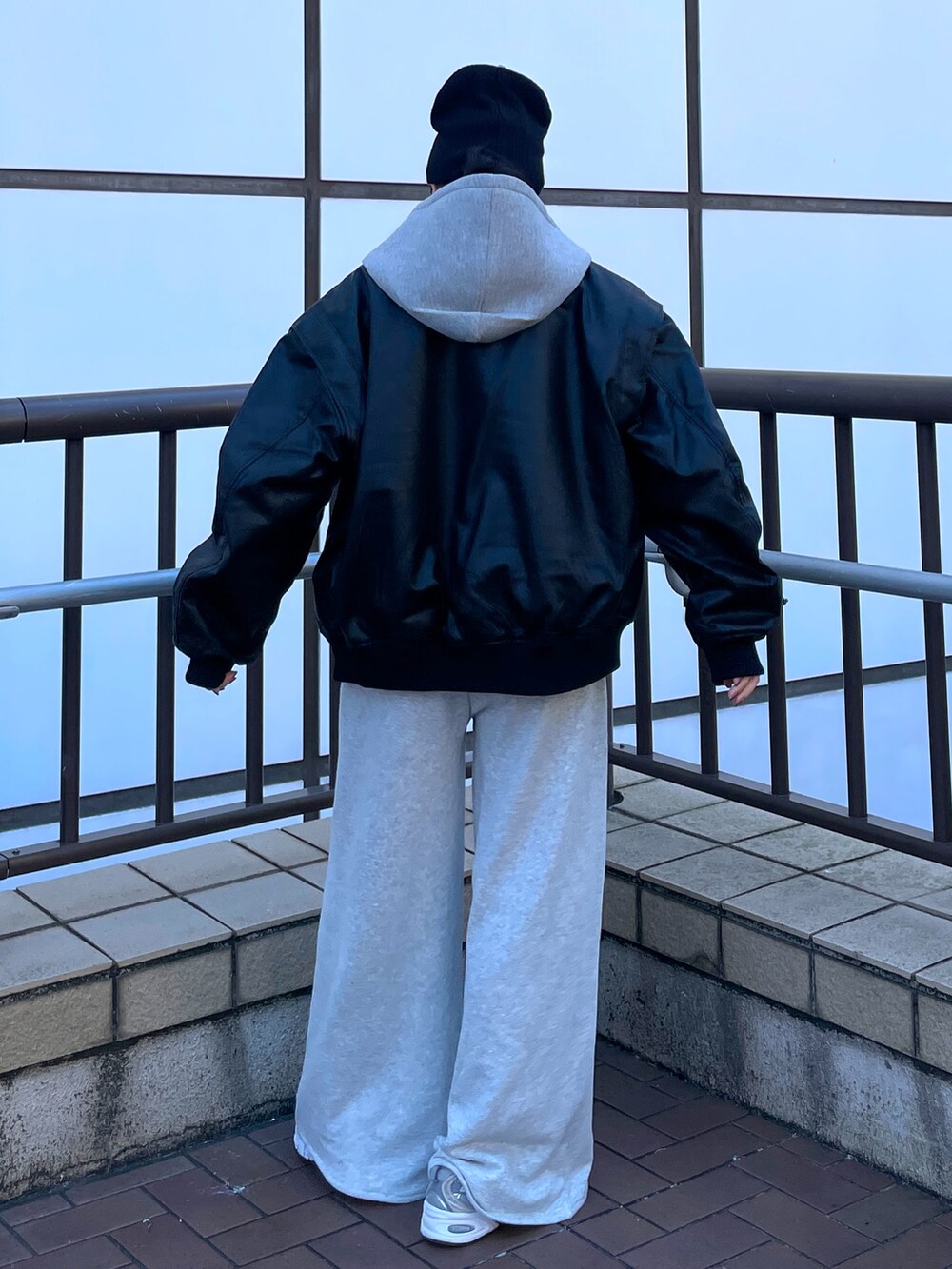 ブラック系のブルゾン、グレー系のパーカー、グレー系のスウェットパンツを着用したレディースの秋コーディネートの3枚目の写真