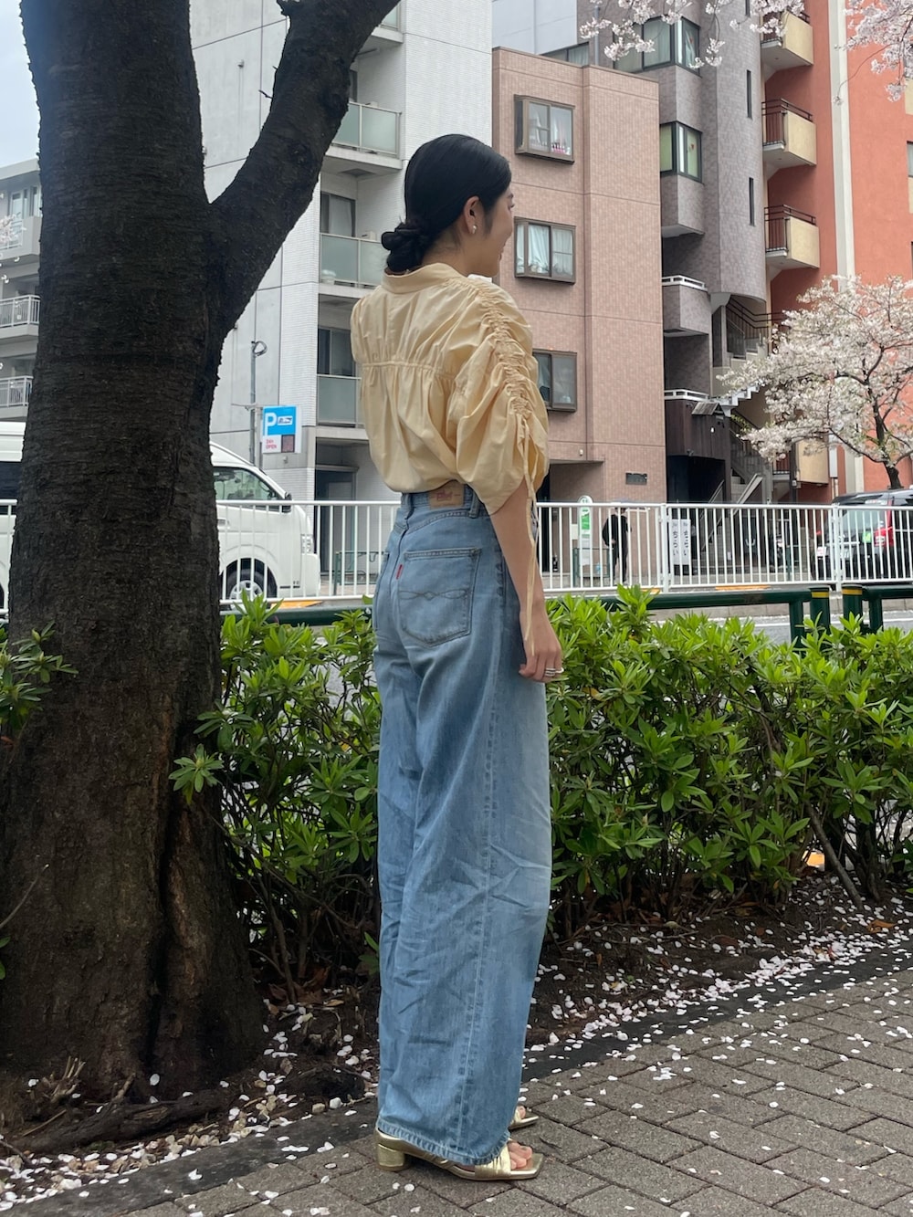 イエロー系のシャツ/ブラウス、ゴールド系のサンダル、ブルー系のデニムパンツを着用したレディースの春コーディネートの3枚目の写真