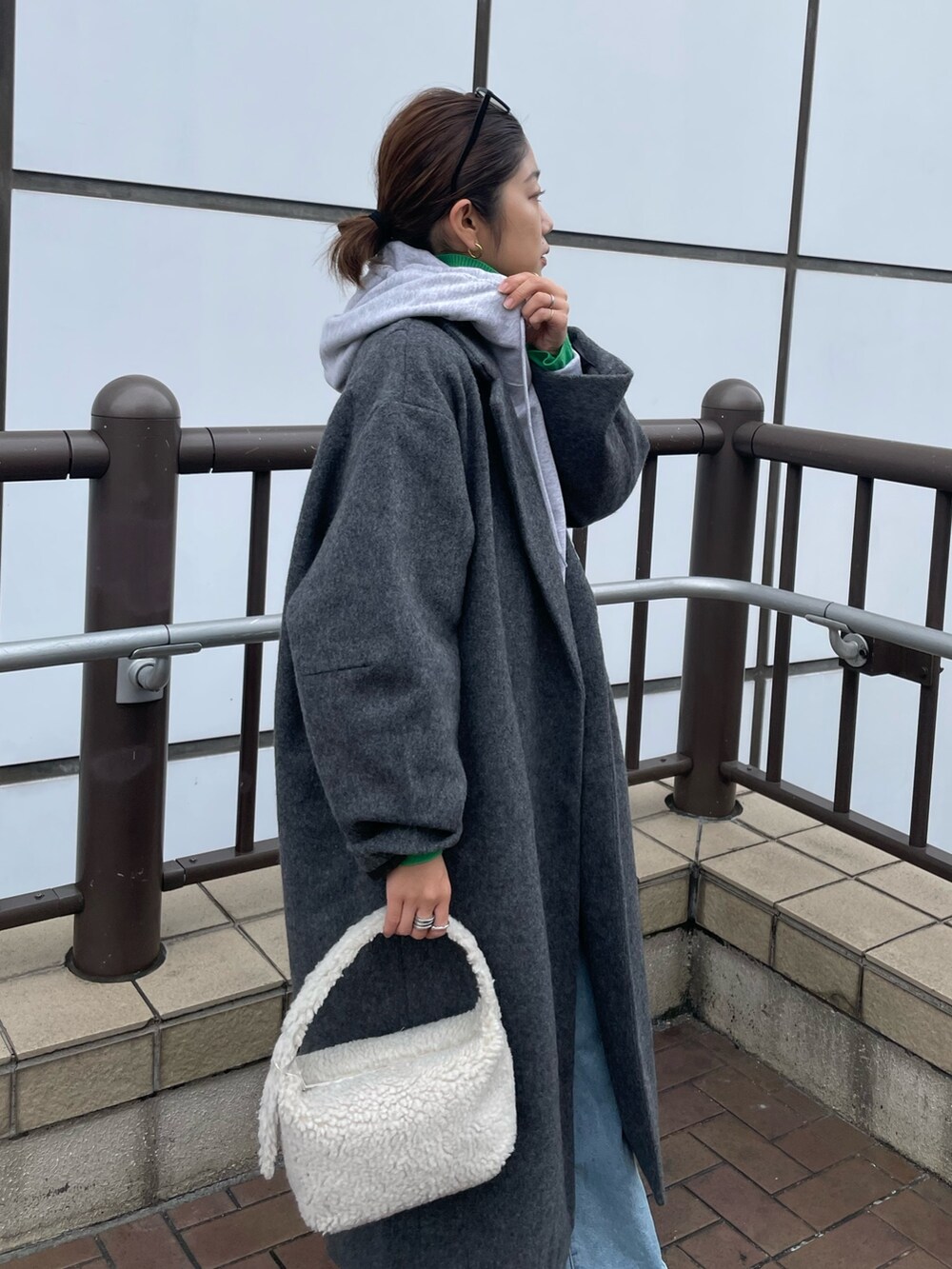 グレー系のパーカー、グリーン系のニット/セーター、ブルー系のデニムパンツを着用したレディースの秋コーディネートの3枚目の写真