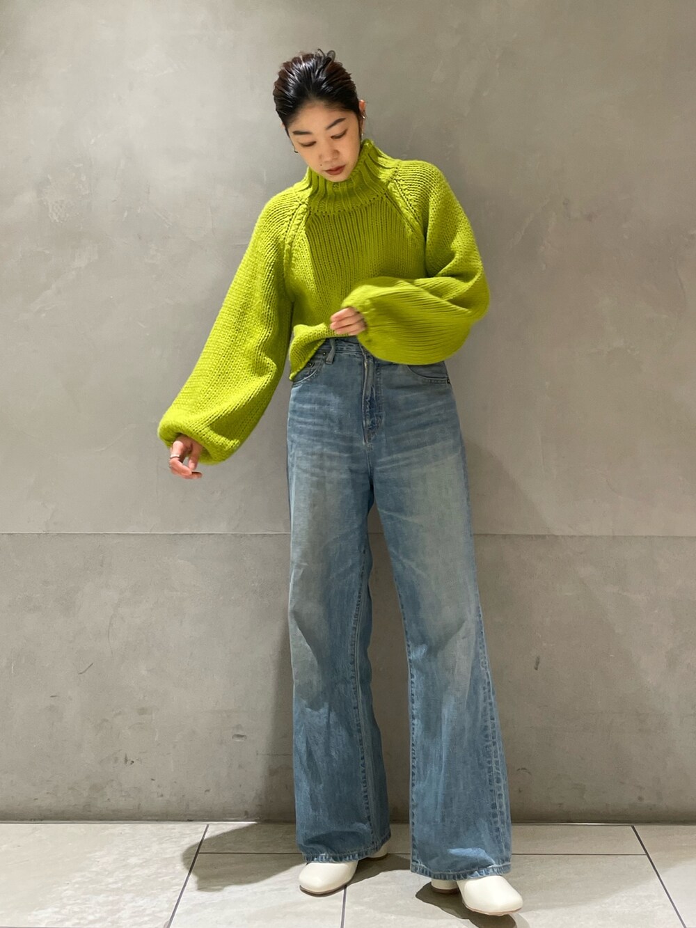 グリーン系のニット/セーター、ブルー系のデニムパンツ、ホワイト系のブーツを着用したレディースの冬コーディネートの5枚目の写真
