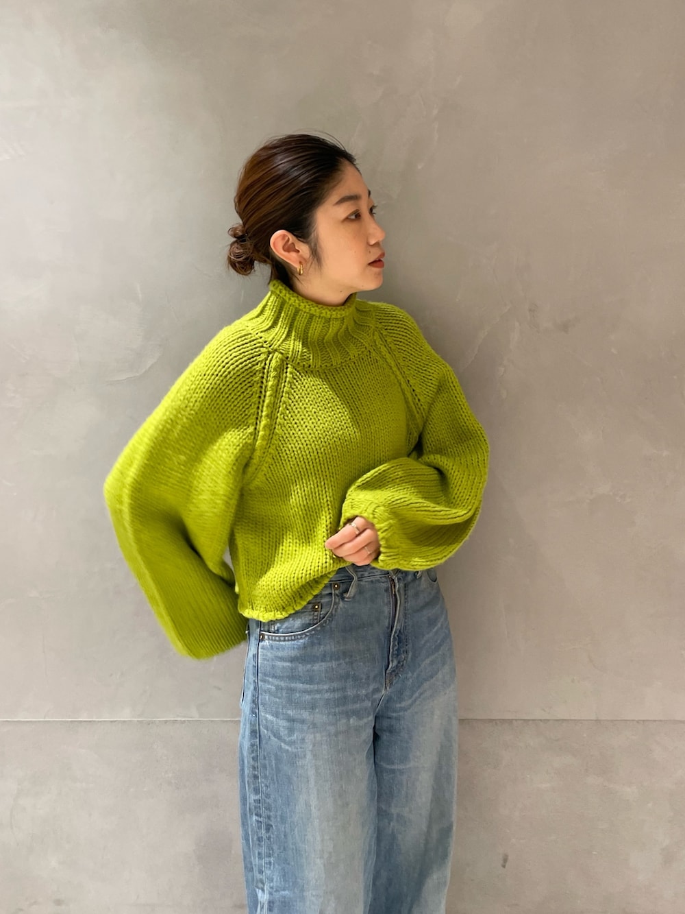 グリーン系のニット/セーター、ブルー系のデニムパンツ、ホワイト系のブーツを着用したレディースの冬コーディネートの3枚目の写真