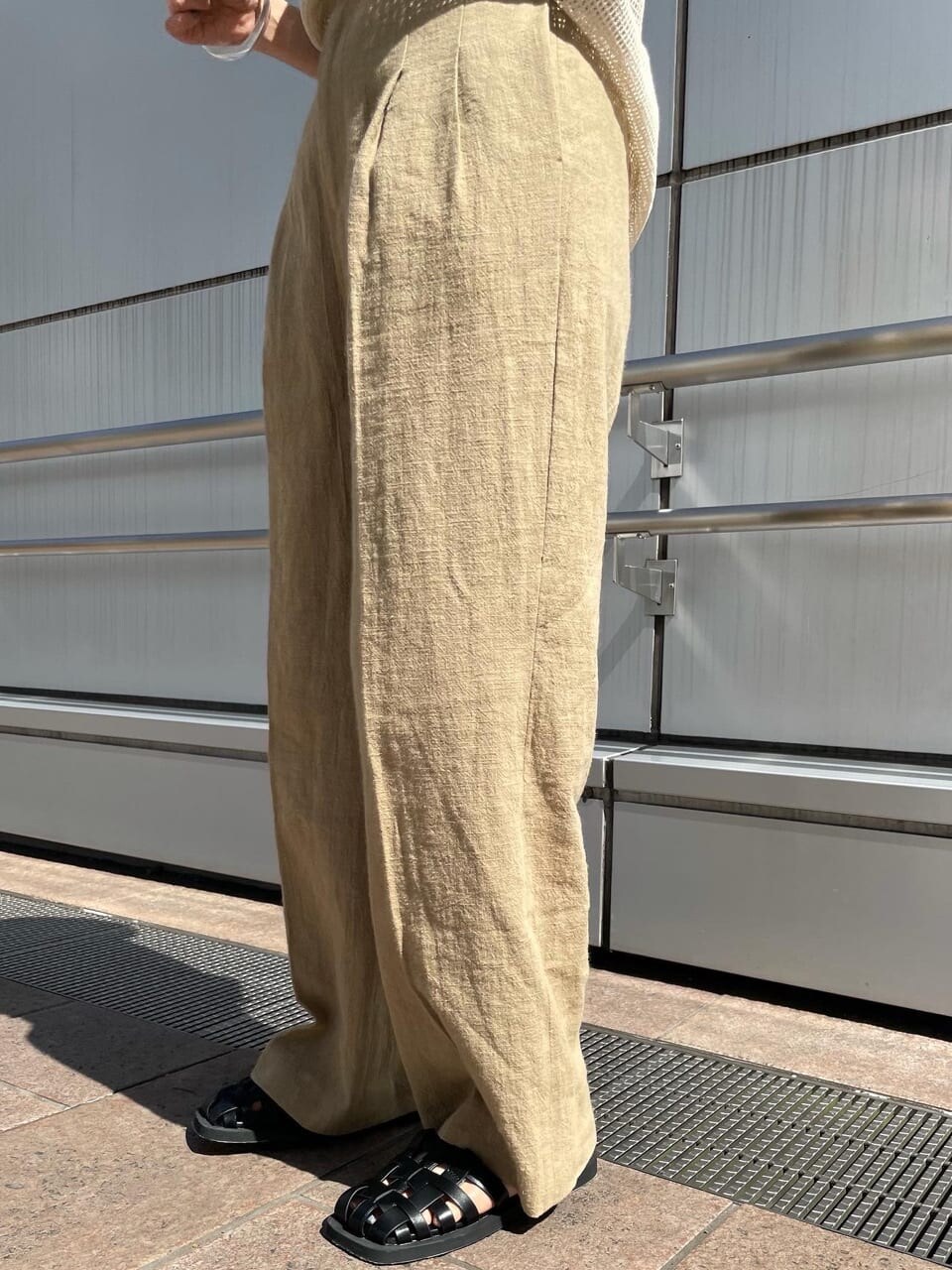 ベージュ系のその他パンツ、ブラック系のサンダル、ホワイト系のTシャツ/カットソーを着用したレディースの春コーディネートの5枚目の写真