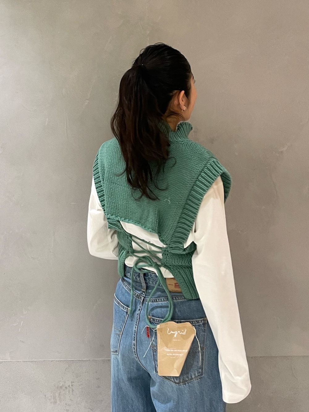 ブルー系のデニムパンツ、グリーン系のワンピース、ゴールド系のパンプスを着用したレディースの冬コーディネートの4枚目の写真