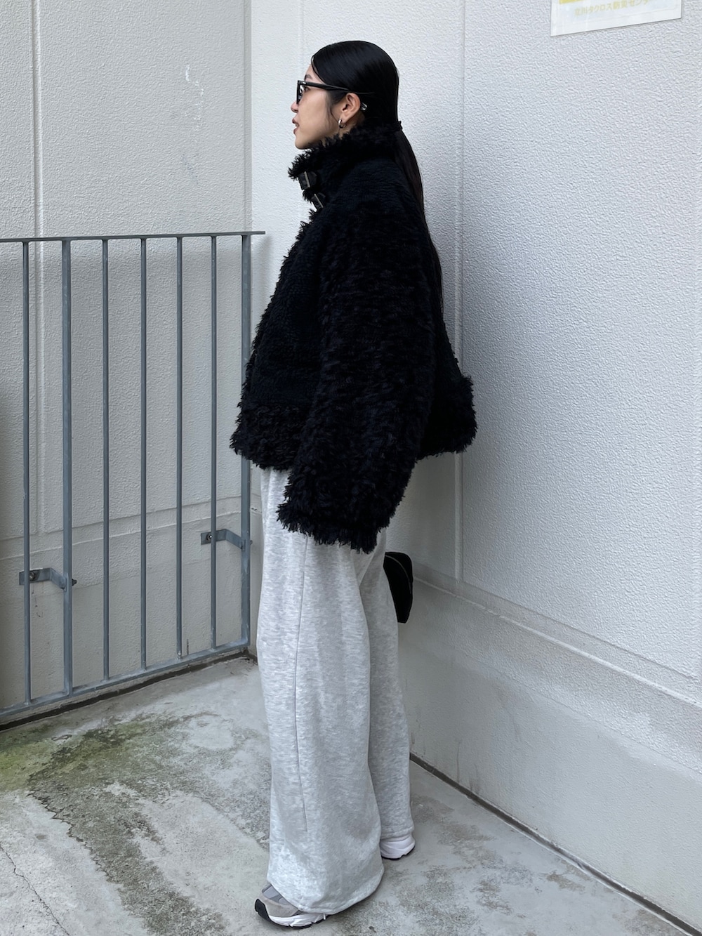 ブラック系のムートンコート、ブラック系のハンドバッグ、グレー系のスウェットパンツを着用したレディースの秋コーディネートの5枚目の写真