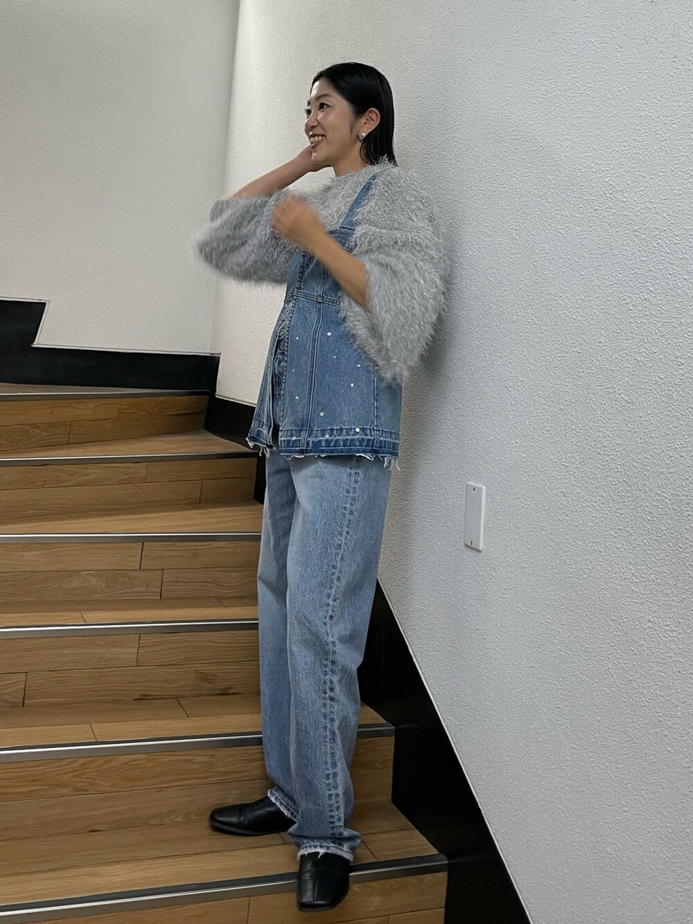 シルバー系のニット/セーター、ブルー系のタンクトップ、ブルー系のデニムパンツを着用したレディースの秋コーディネートの4枚目の写真